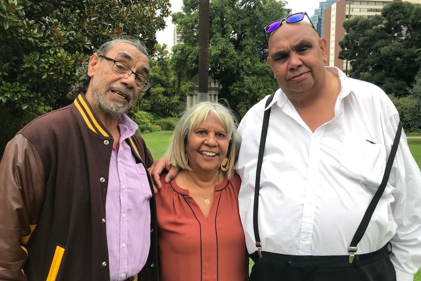 The Edwards siblings stand in a park with their arms around each other.