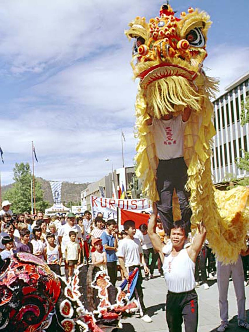 Chinese men wearing a gold and red lion costume.