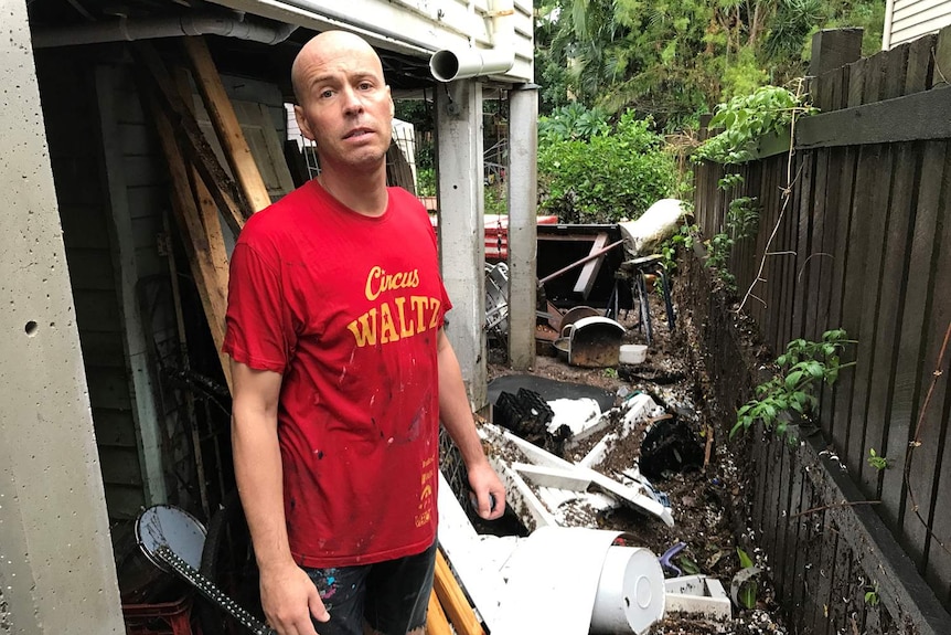 Frans Vogels stands next to debris that was washed out from under his house by storm water