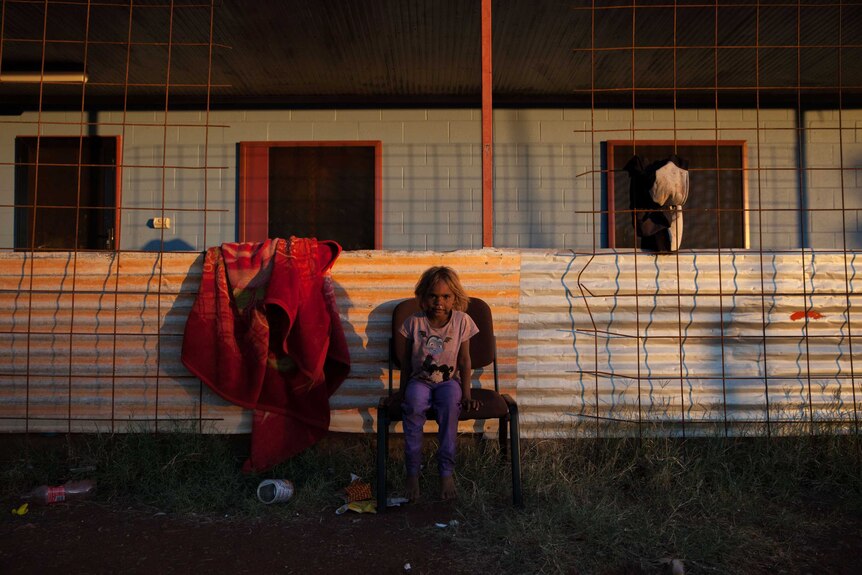 A young girl sits outside her home in Warburton, WA at sunset.