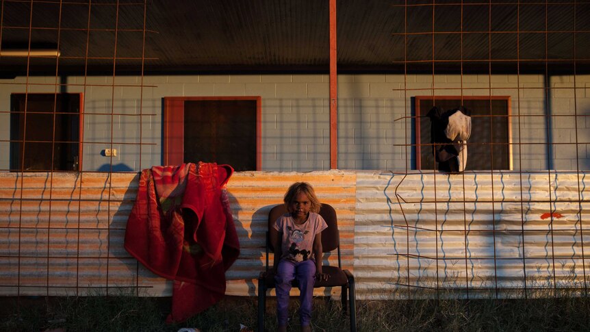 A young girl sits outside her home in Warburton, WA at sunset.