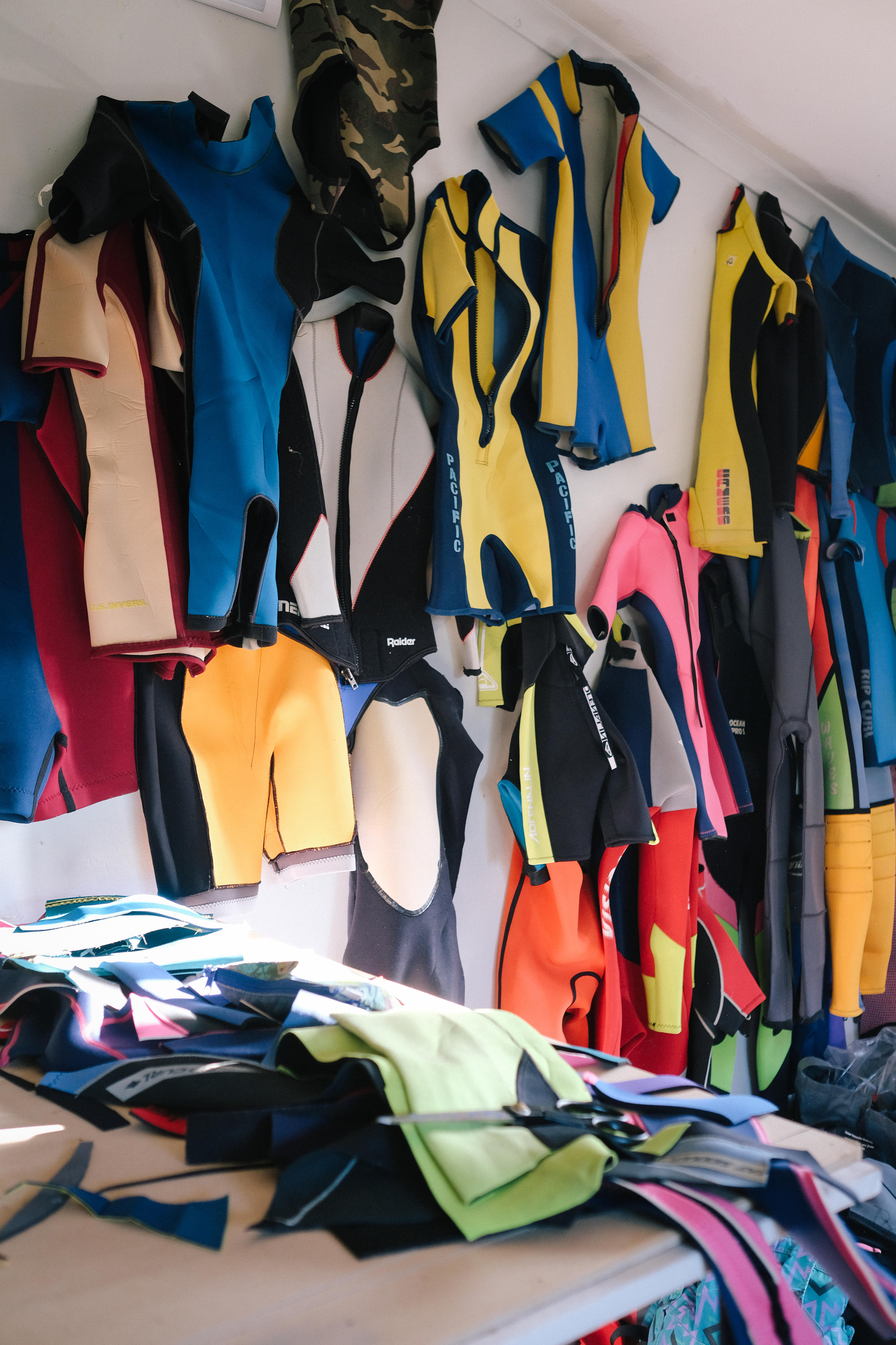 Colourful wetsuits hanging on the wall in an artist's studio 