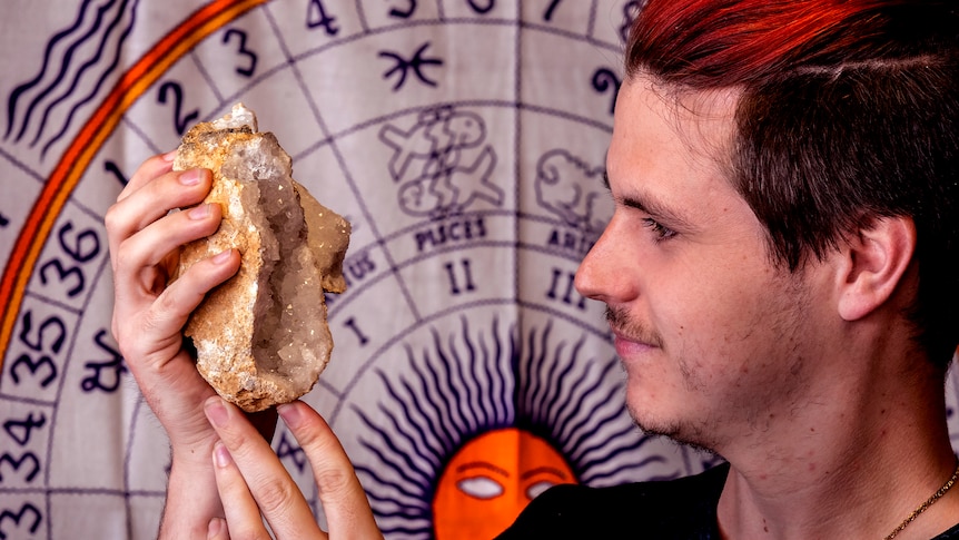 A man holds up a geode rock looking at crystals.