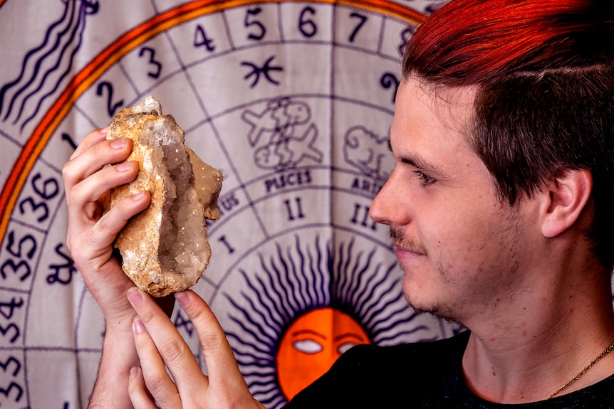 A man holds up a geode rock looking at crystals.