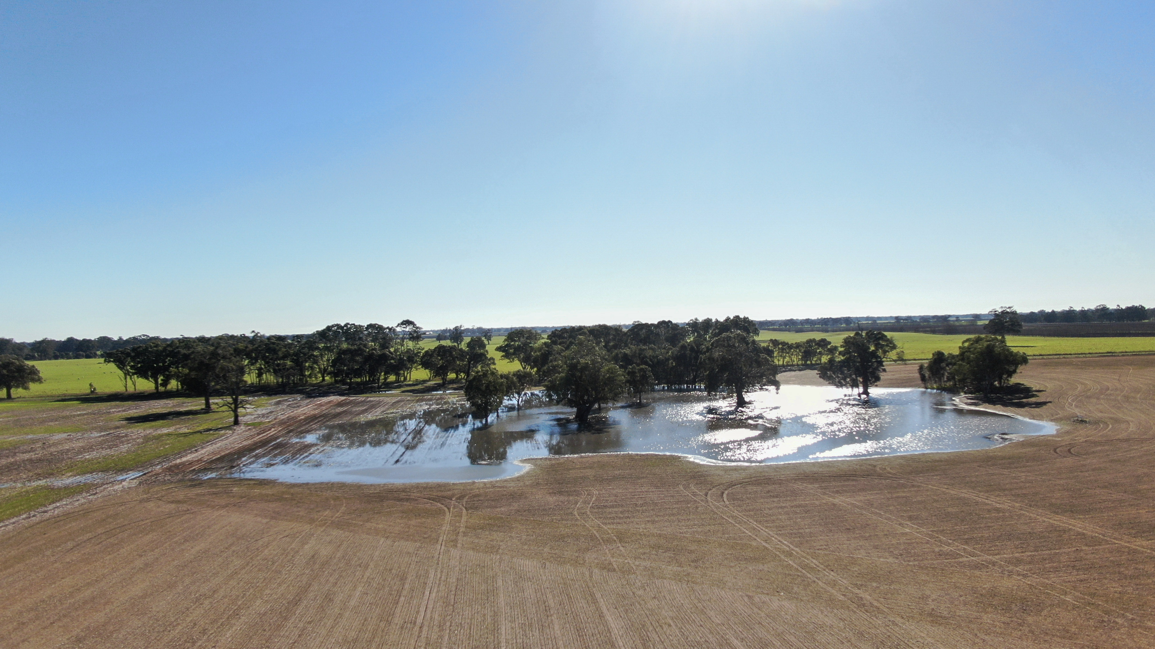 A drone shot of a farm with a water spring in the foreground.