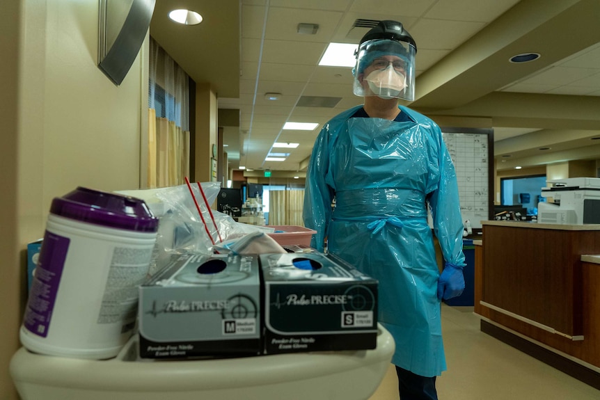 A man in full PPE standing in a hospital corridor