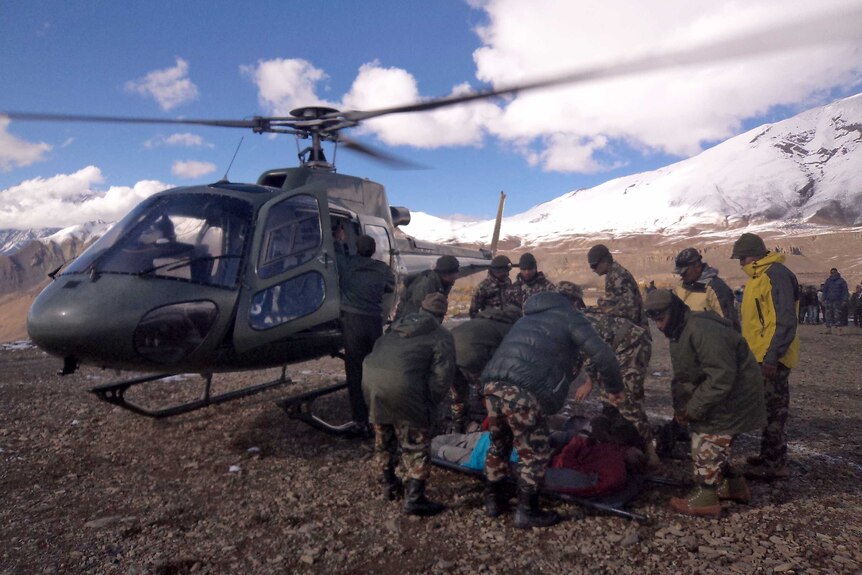 A survivor of a snowstorm is helped into a helicopter