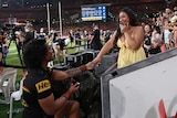 penrith panthers player brian to'o is down on one knee proposing to his partner. she is crying and wearing a pale yellow dress