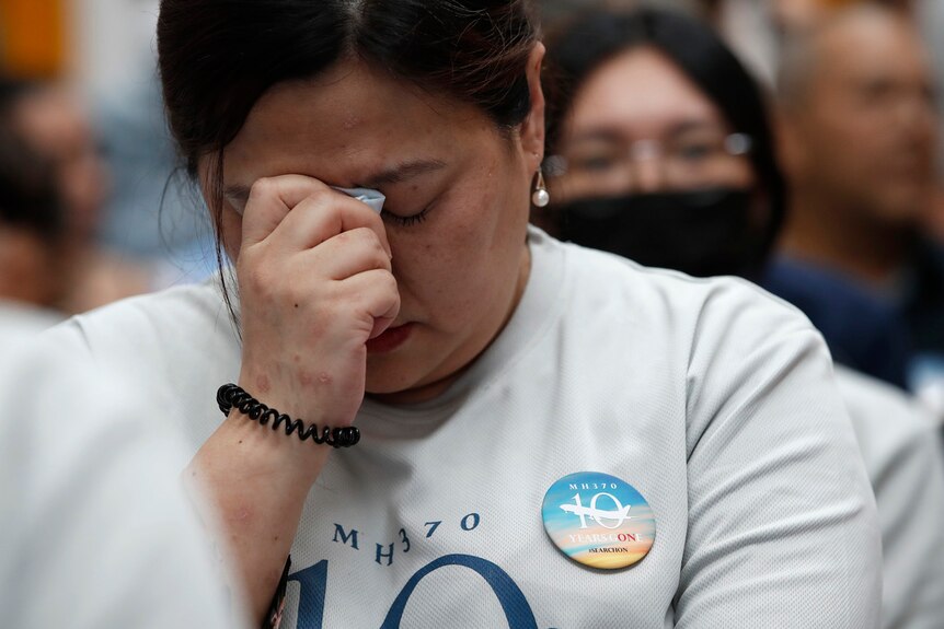 A woman who is a family member of passengers on board the MH370 holds her hand to her head appearign emotional. 