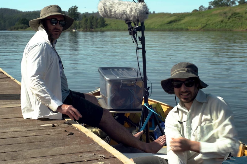 Two men in a boat with sound recording gear.