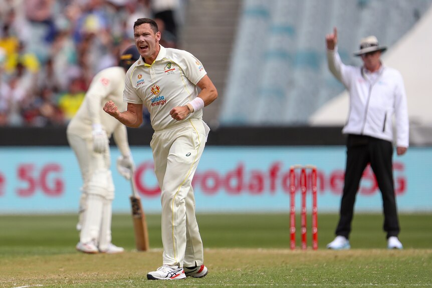 Australia bowler Scott Boland shouts and clenches his fist as the umpire holds up a finger to signal a wicket behind him. 