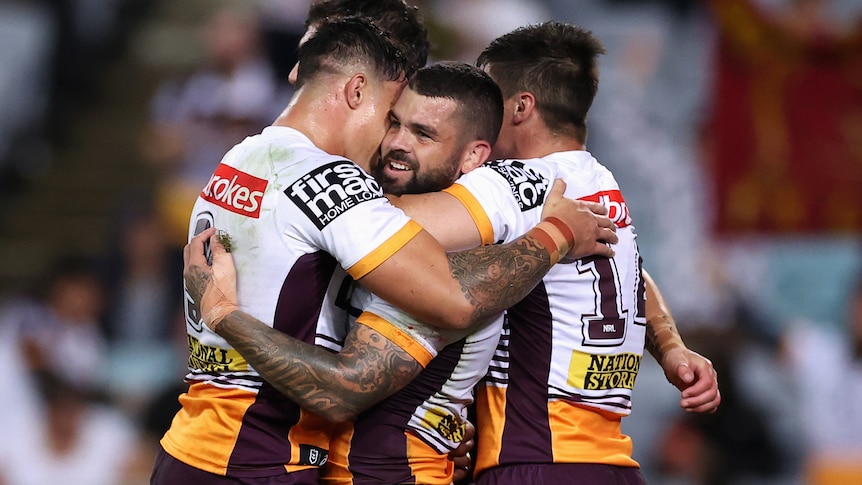 Adam Reynolds is hugged by Brisbane Broncos teammates after scoring a try against South Sydney Rabbitohs in their NRL game.
