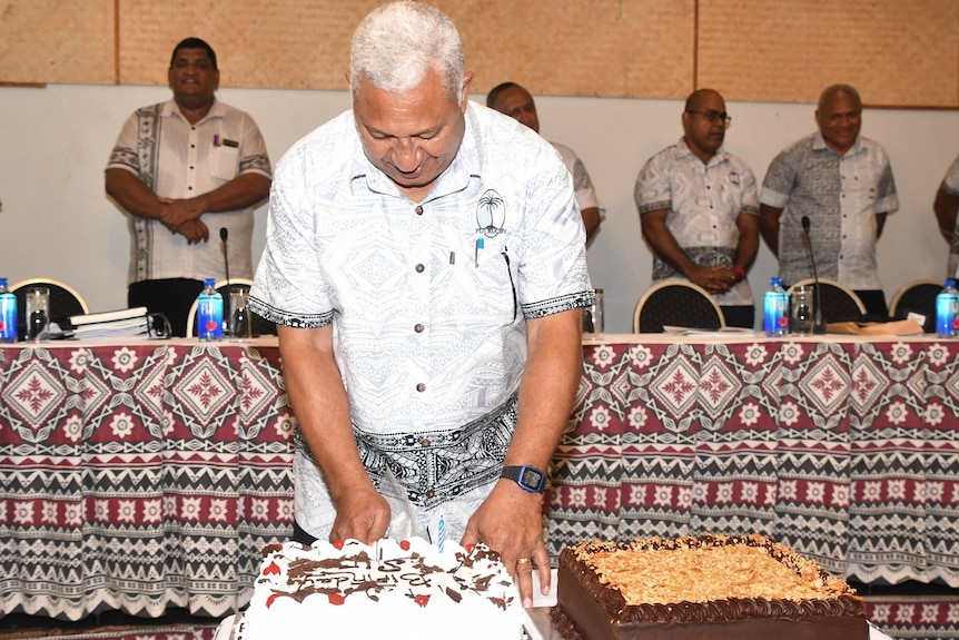 Former Prime Minister of Fiji cuts a birthday cake at a Fiji Rugby Union board meeting.Board in the background 