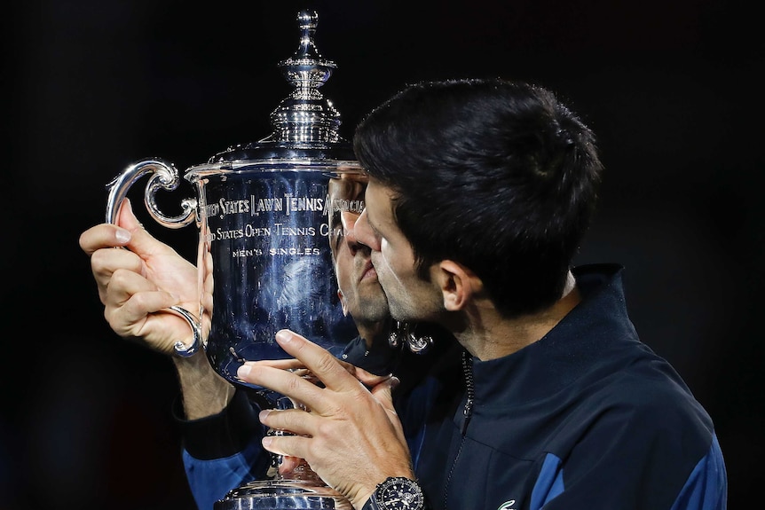 Novak Djokovic kisses a large silver cup.