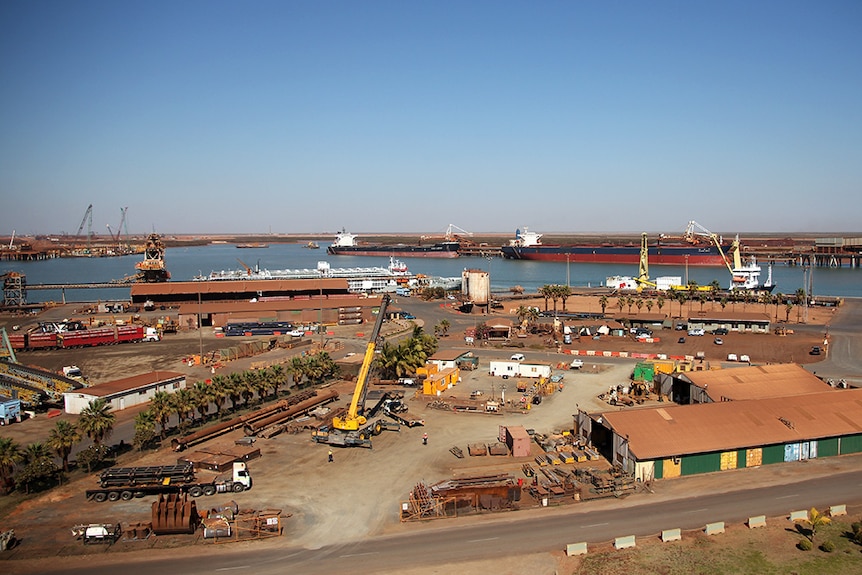 Birds eye view of a an industrial port where shipping containers are loaded onto ships.