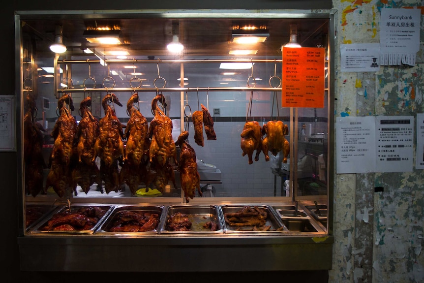 Barbecue roast ducks hanging in Asian butchery shop window.