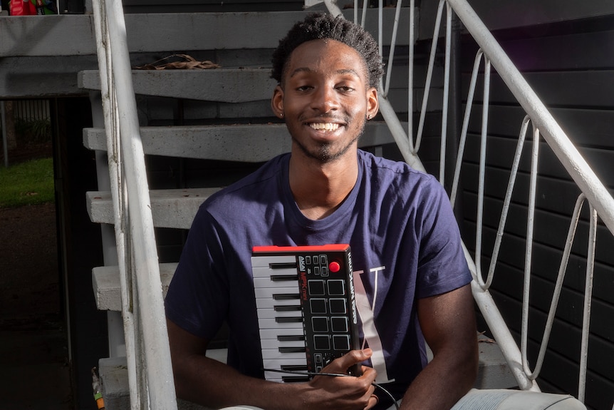 Electronic music producer Egrinya Adie sitting on a step hold and electronic music keyboard