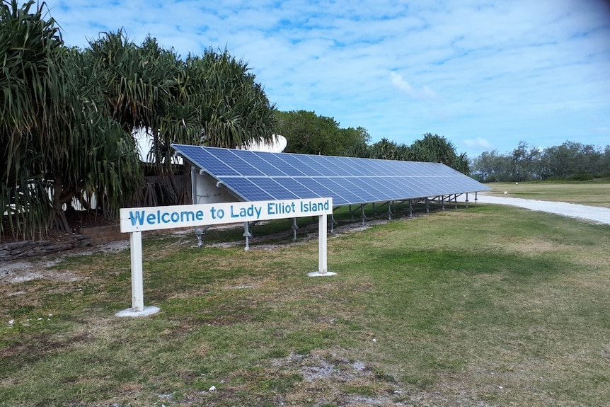 A welcome sign on Lady Elliot Island in front of solar panels.