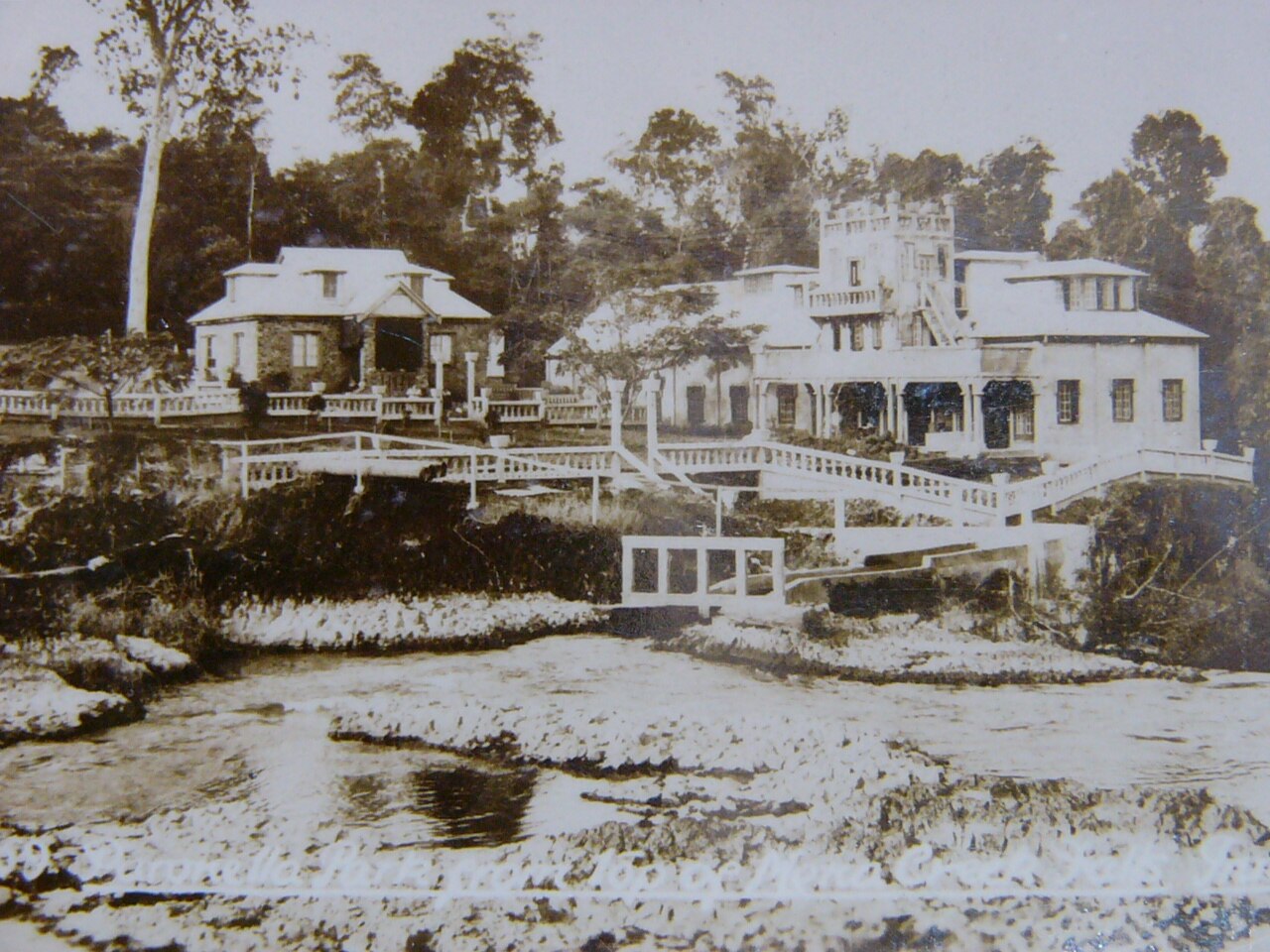 Una foto archivada de un castillo y una casa en un bosque.
