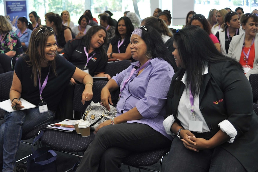 wide shot of laughing Indigenous women in a mining conference.