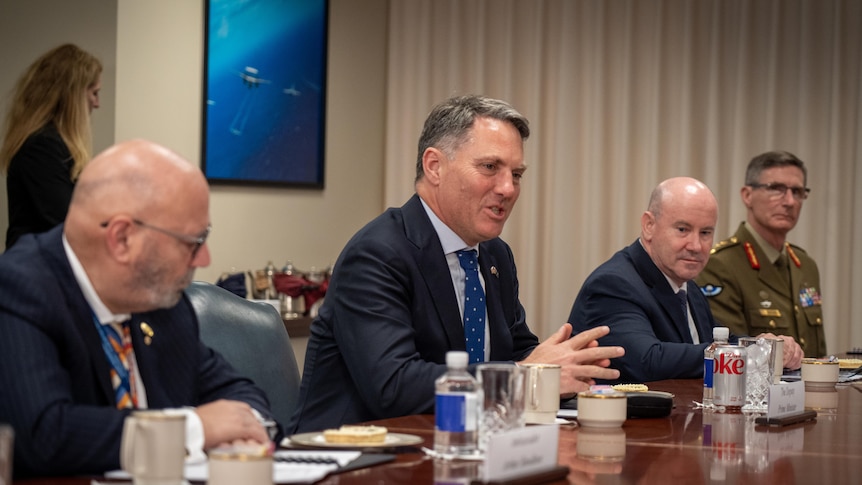 Richard Marles gesticulates at a table 