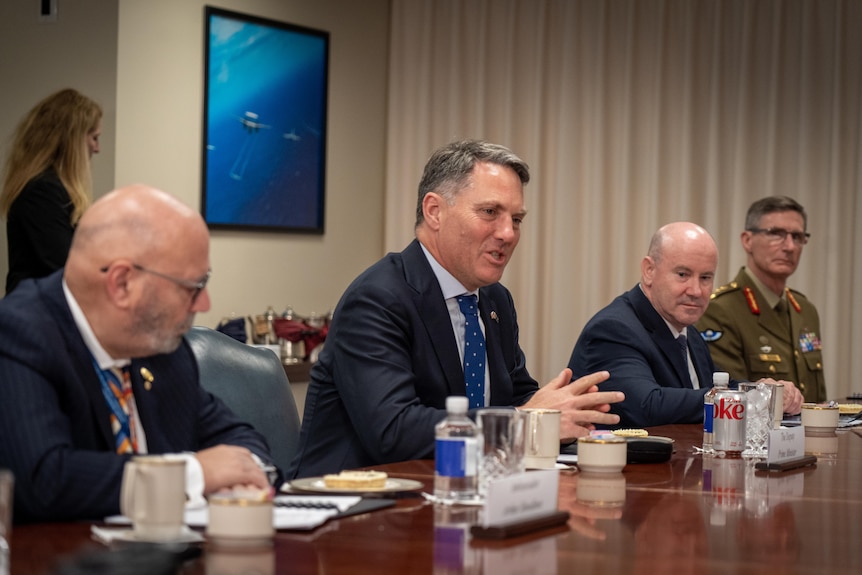 Richard Marles gesticulates at a table 