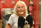 Lady with a dog on her lap smiling at camera