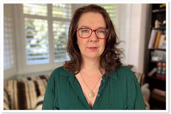 A woman with glasses in a green top looking at the camera