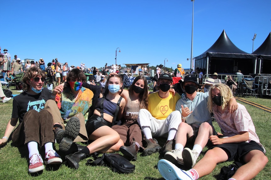 Masked festival-goers at an outdoor music festival. 