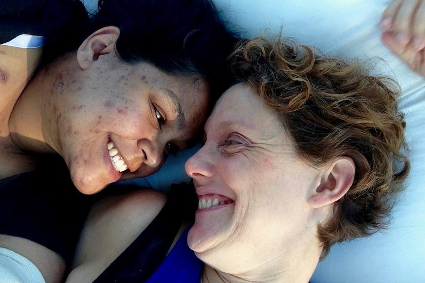 Two women lying down smiling at each other
