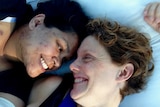 Two women lying down smiling at each other