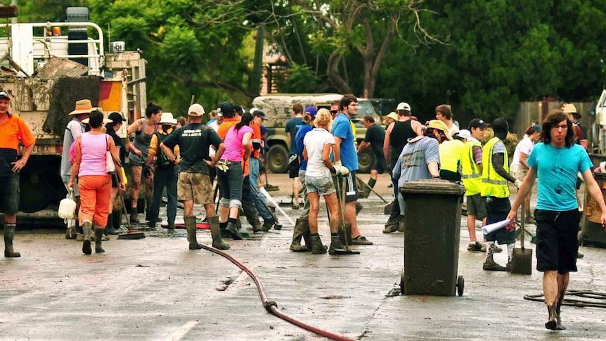 Mud-covered volunteers help clean up in a street in Fairfield in Brisbane on January 15, 2011.