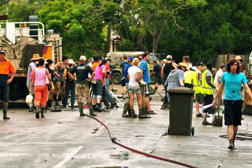 Mud-covered volunteers help clean up in a street in Fairfield on January 15, 2011 after flooding.