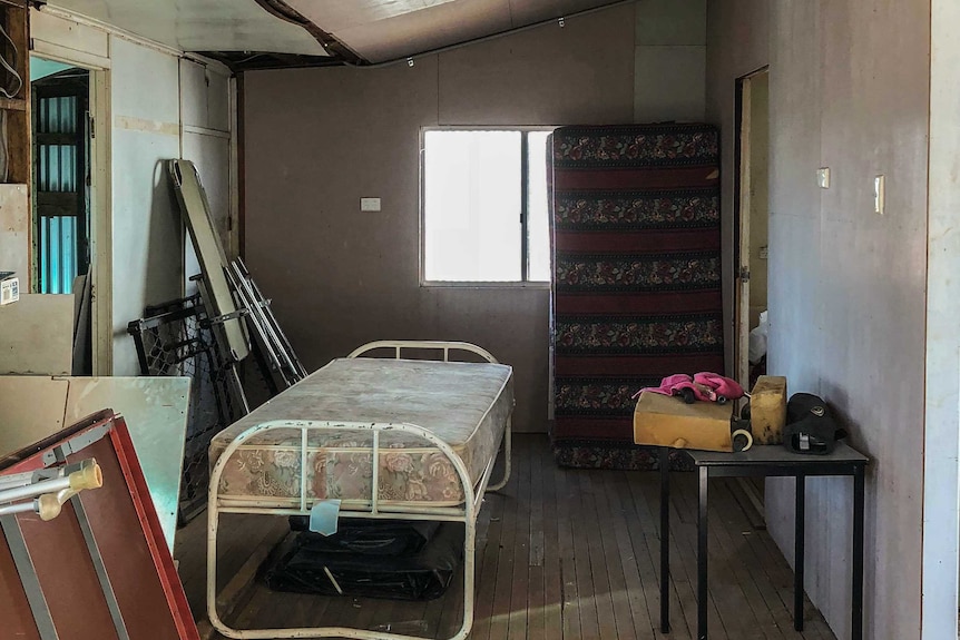 The inside of a shed containing an old bed and mattress.