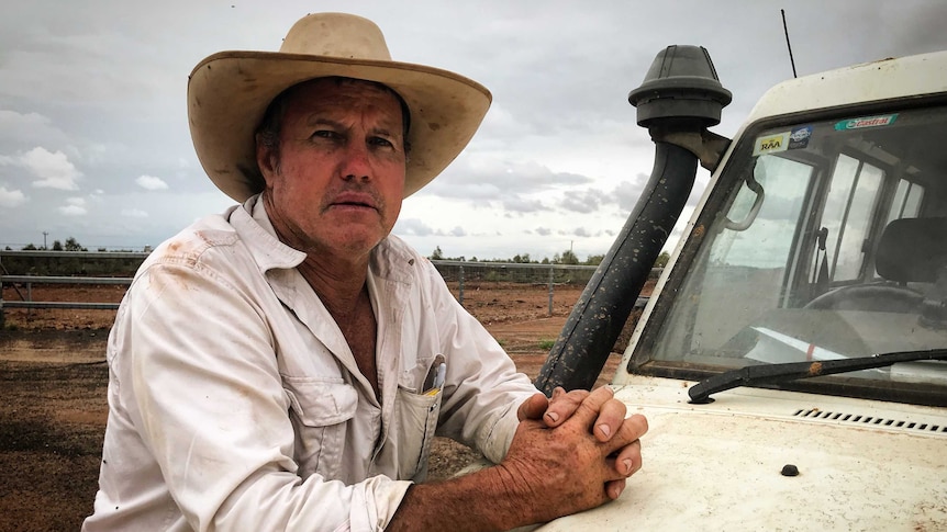 Scott Sargood stands leaning on the bonnet of his ute, looking into the camera and wearing a big hat.