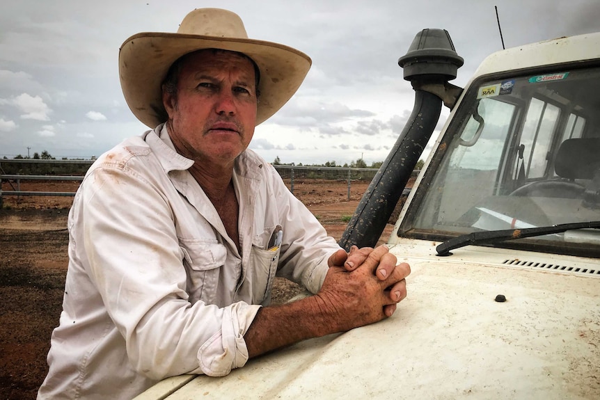 Scott Sargood stands leaning on the bonnet of his ute, looking into the camera and wearing a big hat.