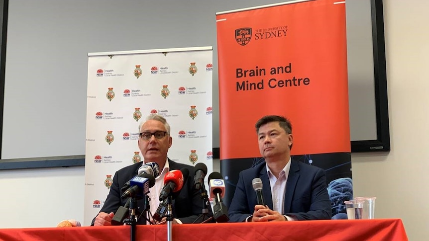 Two academics at a press conference behind a banner "University of Sydney Brain and Mind centre".