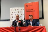 Two academics at a press conference behind a banner "University of Sydney Brain and Mind centre".