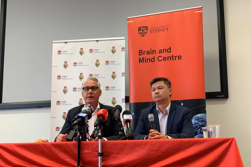 Two academics at a press conference behind a banner "University of Sydney Brain and Mind centre".