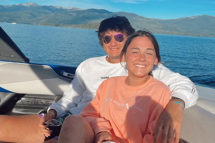 A young woman leans back against a young man on a boat 