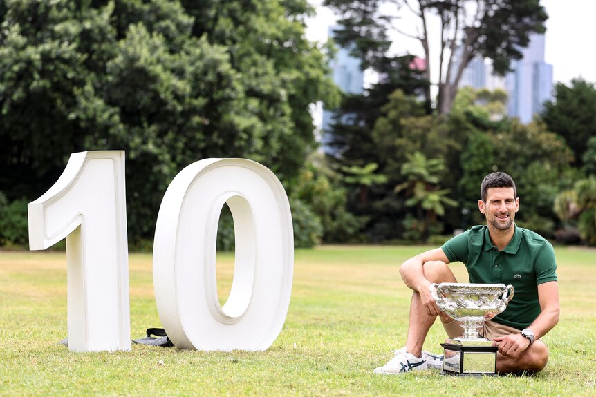 Novak Djokovic poses next to a large 10