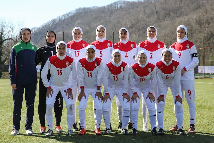 Women footballers pose for a photo before a match