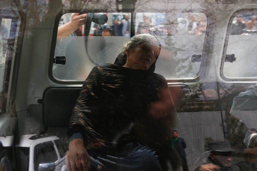 An injured woman sits inside an ambulance during the gun fire outside a military hospital in Kabul