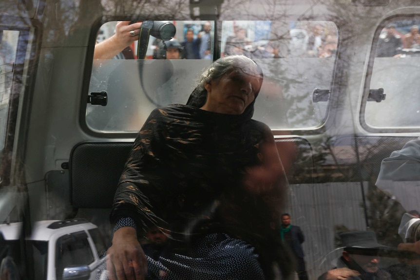 An injured woman sits inside an ambulance during the gun fire outside a military hospital in Kabul