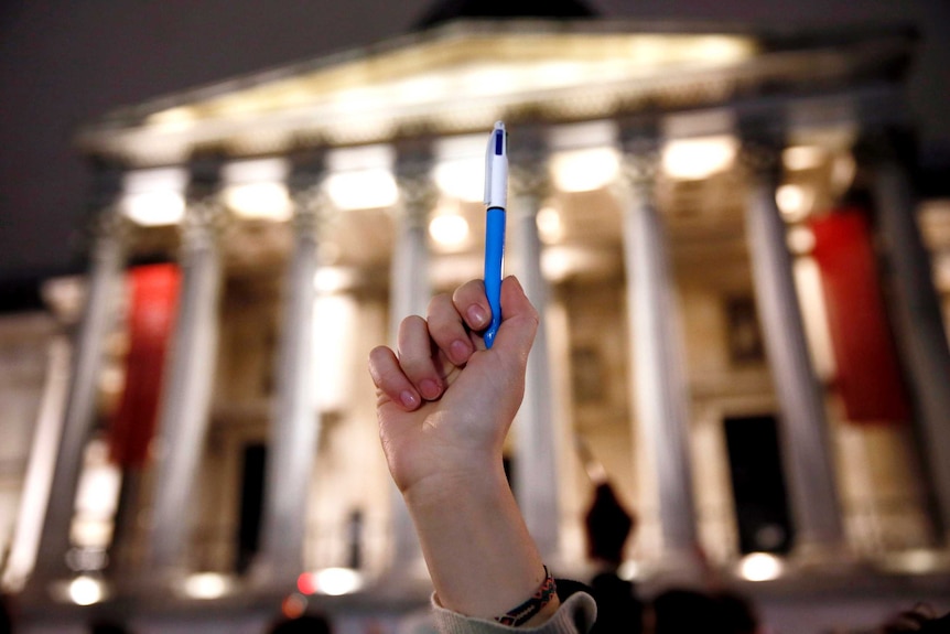 A woman raises a pen during a vigil for the victims of the Charlie Hebdo shooting.