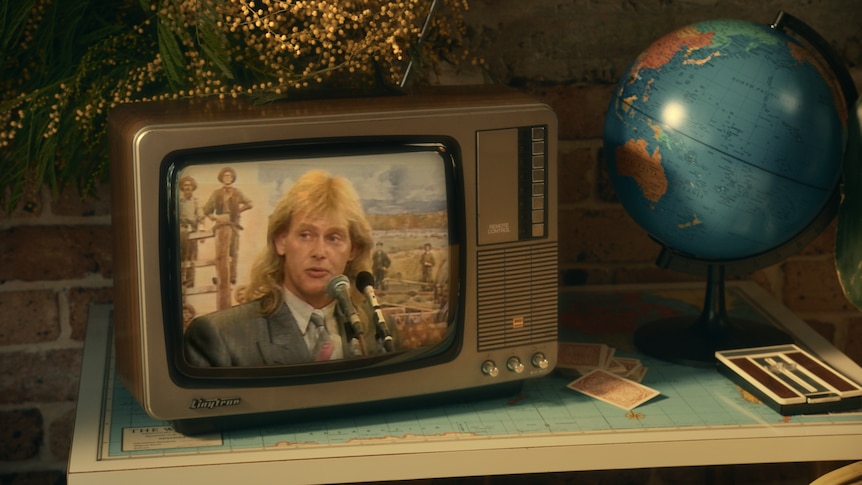 1980s TV with wattle bush on top sitting on a desk with globe 