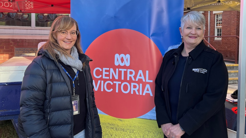 A lady with brown hair stands next to a lady with grey hair in front of an ABC sign.