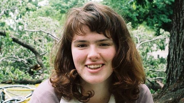 A smiling Eurydice Dixon looks at the camera in a garden in daytime.