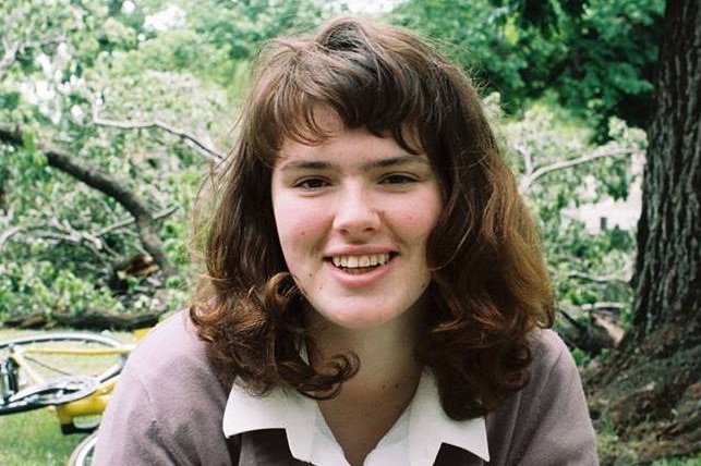 A smiling Eurydice Dixon looks at the camera in a garden in daytime.