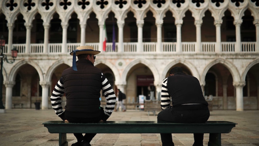 Stripey-shirted gondoliers chat as they wait for customers near St. Mark's square in Venice.
